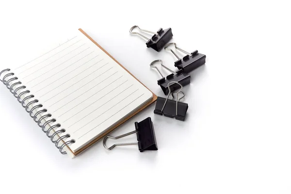 Bürotisch mit einer Gruppe schwarzer Metallbinder-Büroklammern und Notizbuch isoliert auf weiß - Bild — Stockfoto