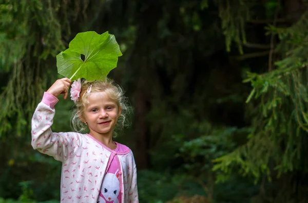 Child with green burdock leaf — Stock Photo, Image