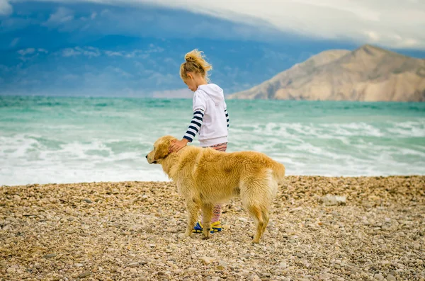 Criança com cão na praia junto ao mar — Fotografia de Stock