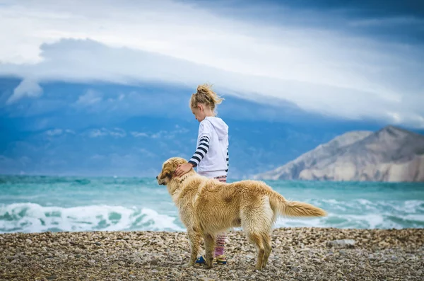 Menina com cão na praia rochosa — Fotografia de Stock