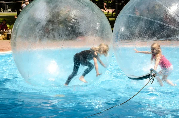 Двое детей играют в супербол в бассейне — стоковое фото