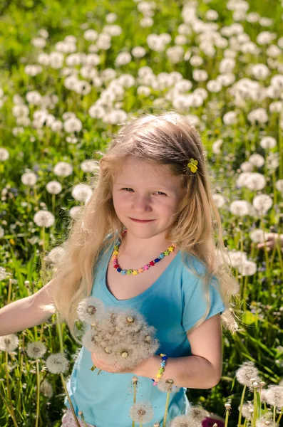 Lachende meisje met paardebloem bloemen — Stockfoto
