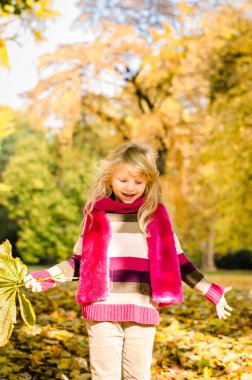 sevimli küçük sarışın kız atma renkli sonbahar parkta bırakır