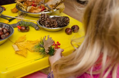 Kestane, kozalak ve meşe palamudundan sonbahar süsü yapan küçük çocuk.