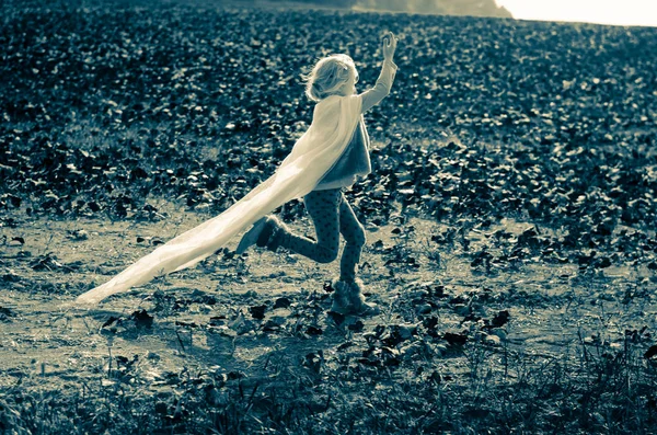 child with mantle running in the field