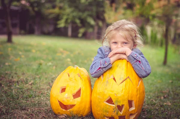 緑の秋の庭にオレンジ色のカボチャと美しいブロンドの女の子 — ストック写真