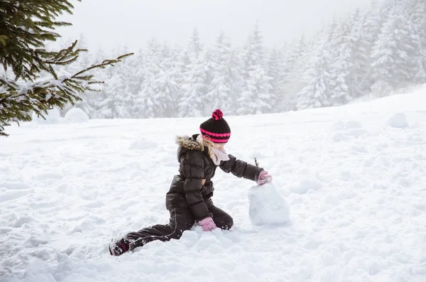 Lilla barnet bygga en snögubbe — Stockfoto