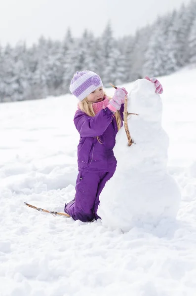 Lilla barnet bygga en snögubbe — Stockfoto