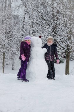 iki güzel çocuk kız kız kardeş bir kardan adam inşa ederken kış parkta oynarken