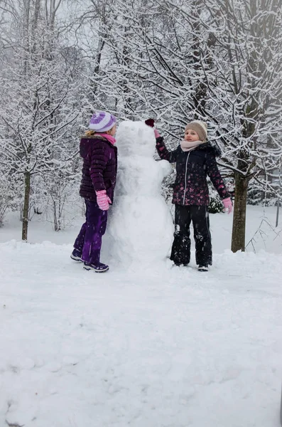 Children in winter park building a snowman — Stock Photo, Image