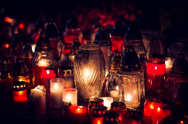 candles burning in lanterns at night during All Saints Day 