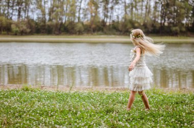 pembe elbiseli peri yeşil çim olarak nehir kenarında dans uzun sarı saçlı güzel beyaz kız