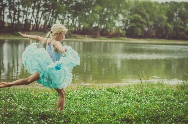 無料川の横にある牧草地の緑の自然を舞う青いドレスの小さな子 — ストック写真