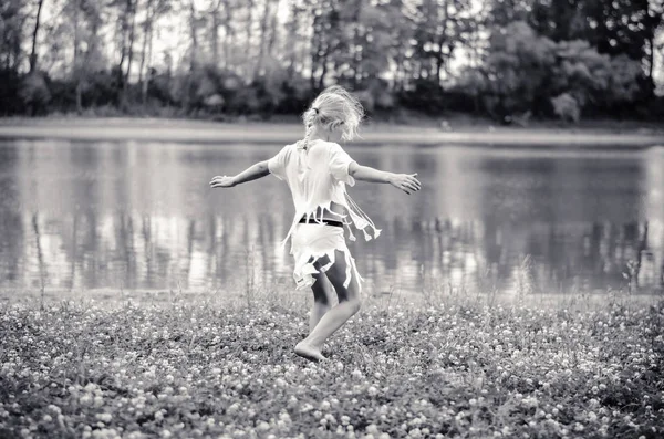 Dziewczynka Długimi Blond Włosami Białej Sukni Tańczy Zielonej Trawie Przez — Zdjęcie stockowe