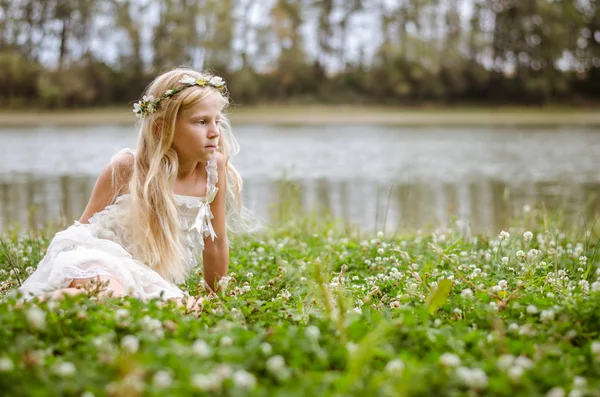 pembe elbiseli oturma nehrin yanında yeşil çim peri kadar yalnız uzun sarı saçlı güzel sasd beyaz kız