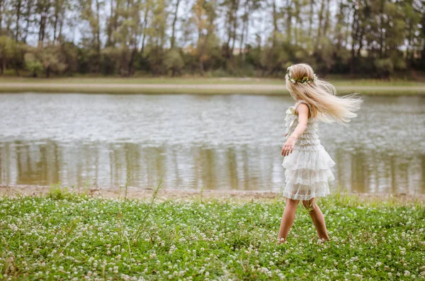 pembe elbiseli peri yeşil çim olarak nehir kenarında dans uzun sarı saçlı güzel beyaz kız