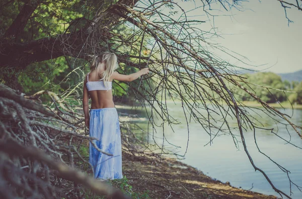 川の土手で木の枝の下を歩く少女 — ストック写真