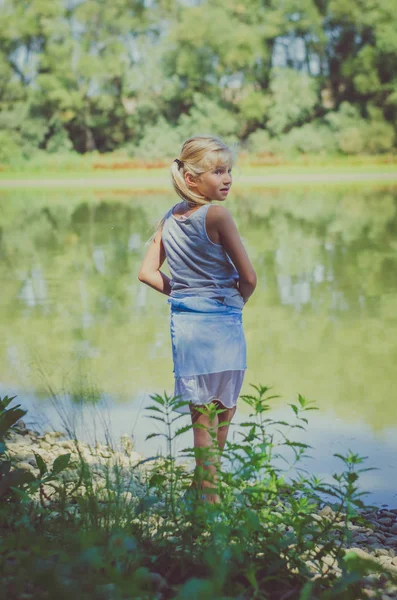 Bambino lungo il fiume guardando indietro — Foto Stock