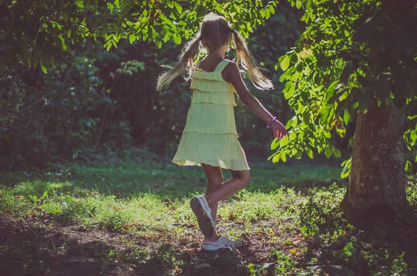 Menina encantadora em vestido amarelo dançando na grama junto ao rio — Fotografia de Stock