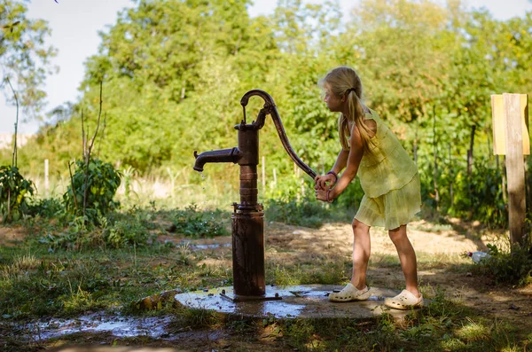 Criança bombeando água do poço de água — Fotografia de Stock