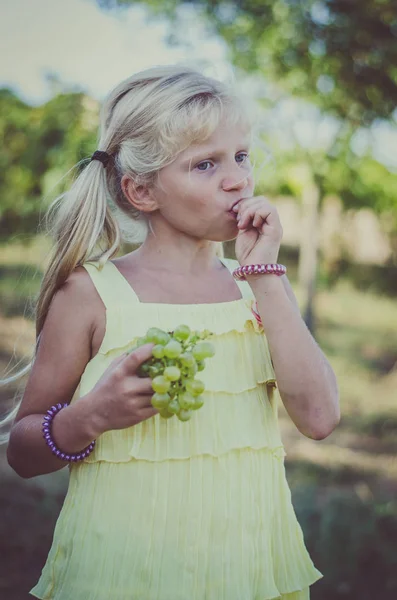 ブドウを食べて黄色のドレスでちょっと素敵な女の子 — ストック写真