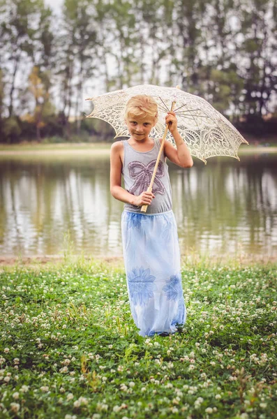 Menina com guarda-chuva branco junto ao rio sorrindo — Fotografia de Stock