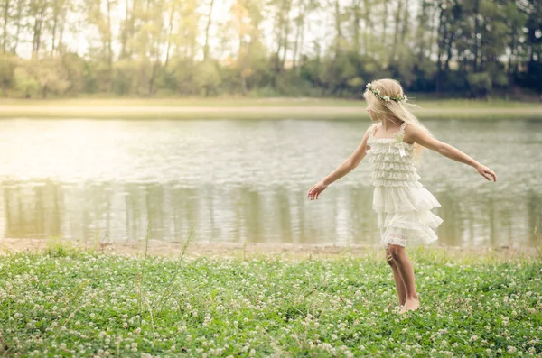 Petite jolie fille dansant dans l'herbe au bord de la rivière — Photo