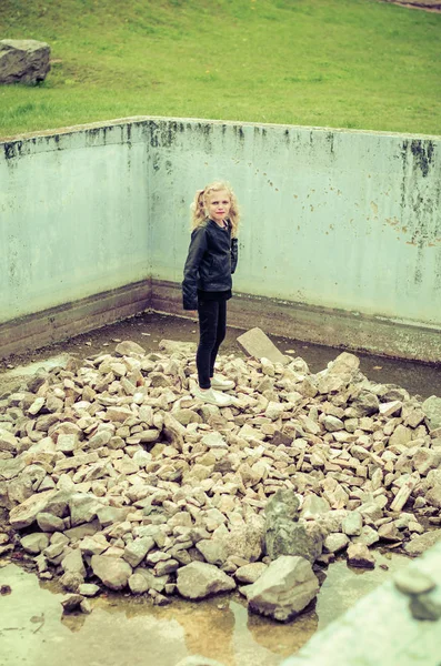 Child in empty swimming pool full of rocks — Stock Photo, Image