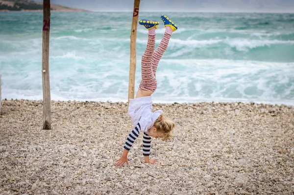 Liten Blond Flicka Gör Gymnastik Den Steniga Stranden Vid Havet — Stockfoto