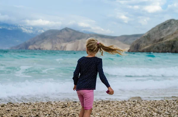 Lilla Flickan Tillbaka Visa Den Steniga Stranden Med Tunga Havet — Stockfoto