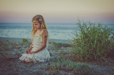 uzun sarı saçlı deniz kenarında oturan üzgün kız