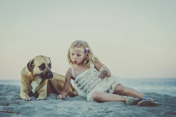 Menina e cão deitado na praia — Fotografia de Stock