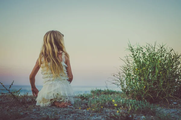 Menina com longos cabelos loiros sentados à beira-mar — Fotografia de Stock