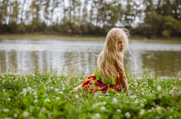 Smutná dívka sedí sám v trávě u řeky — Stock fotografie