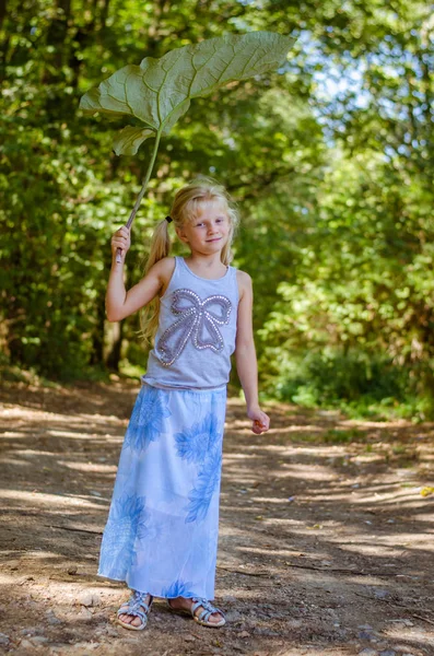 Little lovely girl holding a green burdock over her head — Stock Photo, Image