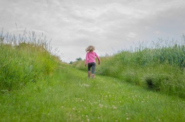 girl with long blond hair back view walking in rural path clipart