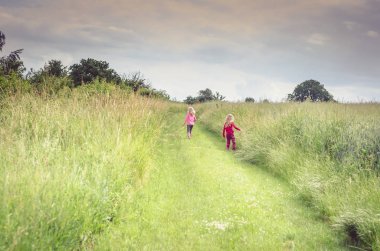 Kız meadows arasında yeşil kırsal yolunda yürümek