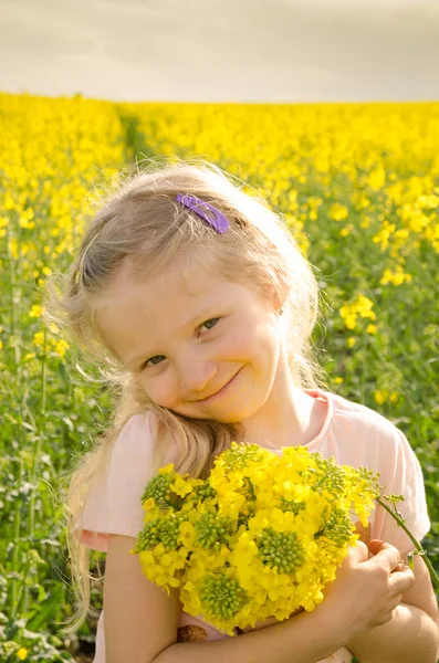 Criança segurando flores de colza amarelas — Fotografia de Stock