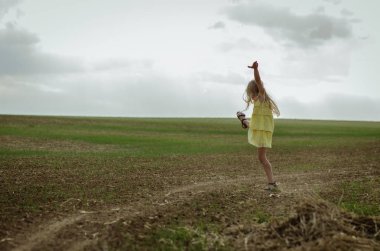 Sarı elbiseli, kırsal yolda dans eden mutlu çocuk.