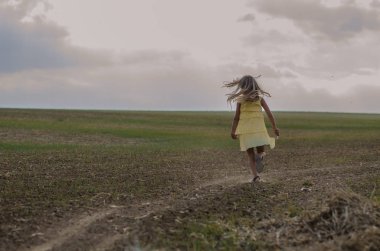 Sarı elbiseli, kırsal yolda dans eden mutlu çocuk.