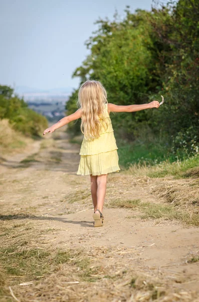 Gelukkig kind dansen op het platteland pad in gele jurk — Stockfoto