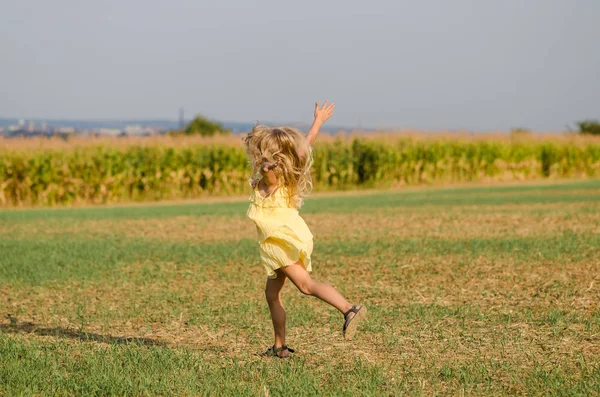 Danza selvaggia di bambino felice nel percorso rurale in abito giallo — Foto Stock