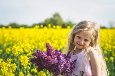 Ellerinde leylak buketi olan beyaz bir çocuk.