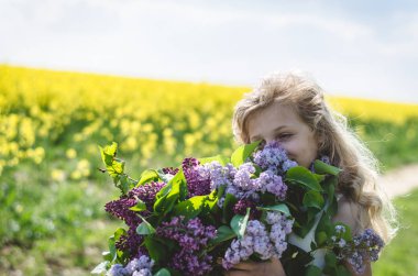 Ellerinde leylak buketi olan beyaz bir çocuk.