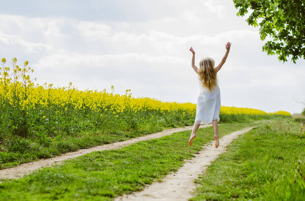 strange blond girl jumping in rural path  back view