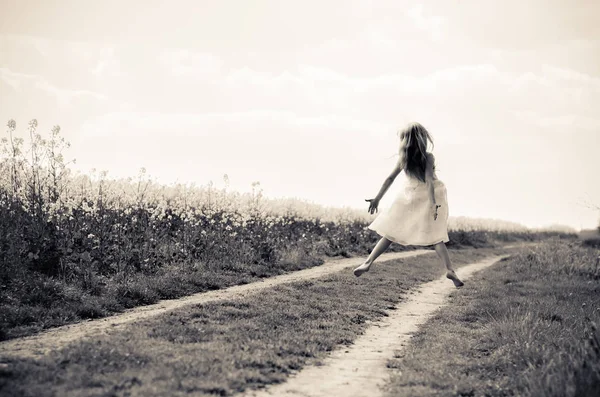 Linda menina loira pulando no caminho rural — Fotografia de Stock
