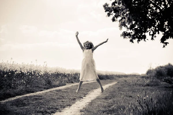 Vacker blond flicka hoppar på landsbygden väg — Stockfoto
