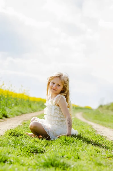 Encantador niño caucásico sentado solo en la naturaleza de primavera —  Fotos de Stock