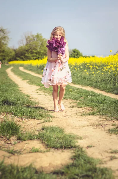 Encantadora criança caucasiana com buquê de lilás nas mãos — Fotografia de Stock