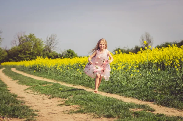 Menina encantadora em vestido de verão correndo no caminho rural na natureza verde — Fotografia de Stock